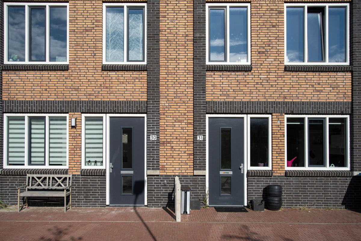 A modern brick house facade featuring large windows and contrasting doors, showcasing contemporary architecture.