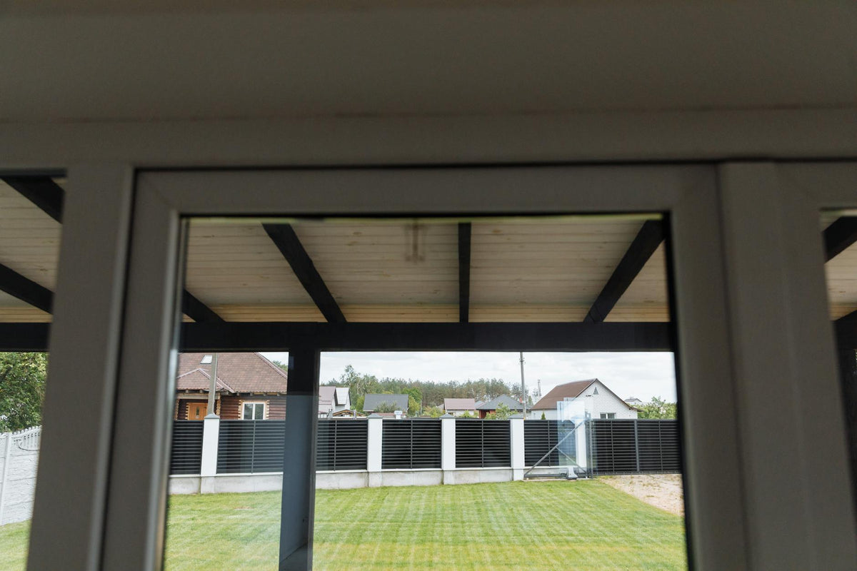 A view through a window overlooking a tidy suburban backyard with green grass.