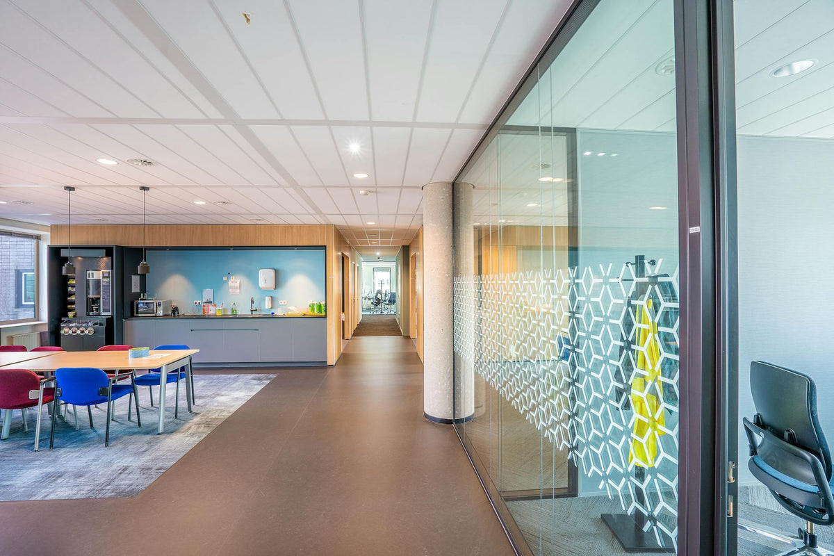 A sleek modern office space featuring colorful seating and a kitchenette in a bright, well-lit environment.