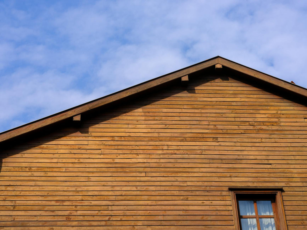Detailed shot of a rustic wooden building facade contrasting against a bright blue sky.