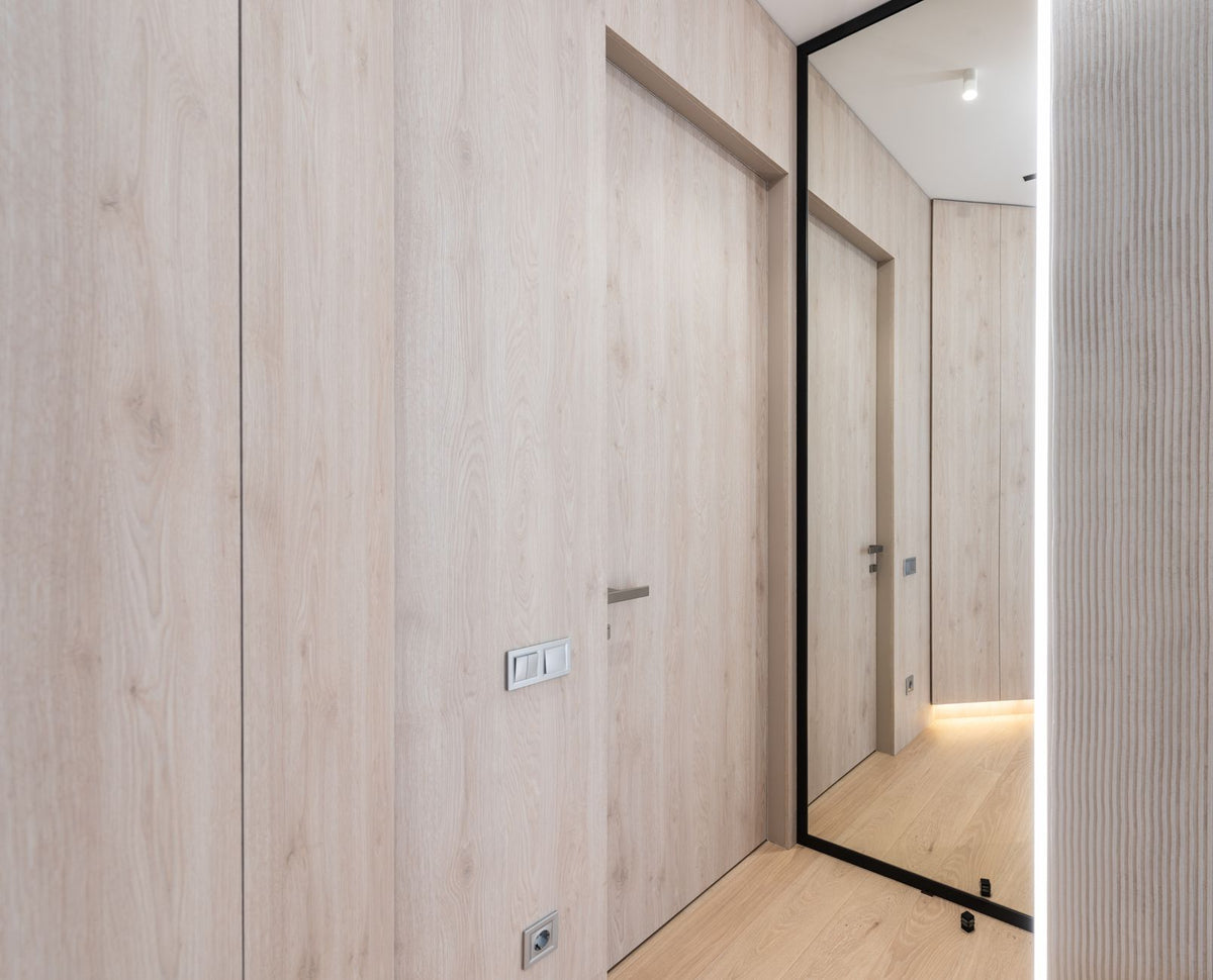 Interior of light empty corridor with door next to mirror in modern apartment