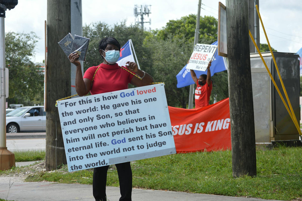 Individuals preaching with religious signs on city streets, wearing masks for protection.
