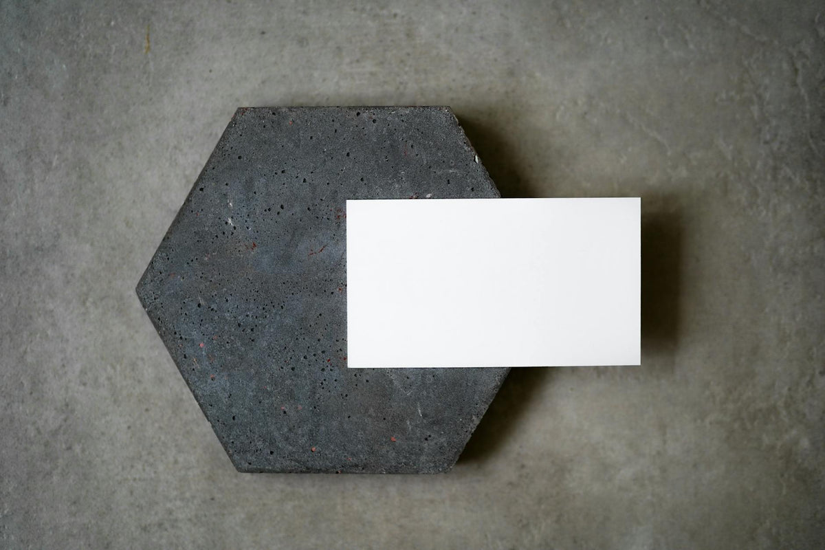 A blank white card placed on a textured concrete hexagon for a minimalist design.