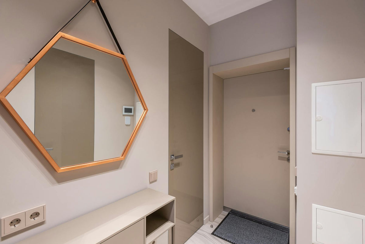 Stylish contemporary flat hallway design with geometrical mirror on wall and empty shelves