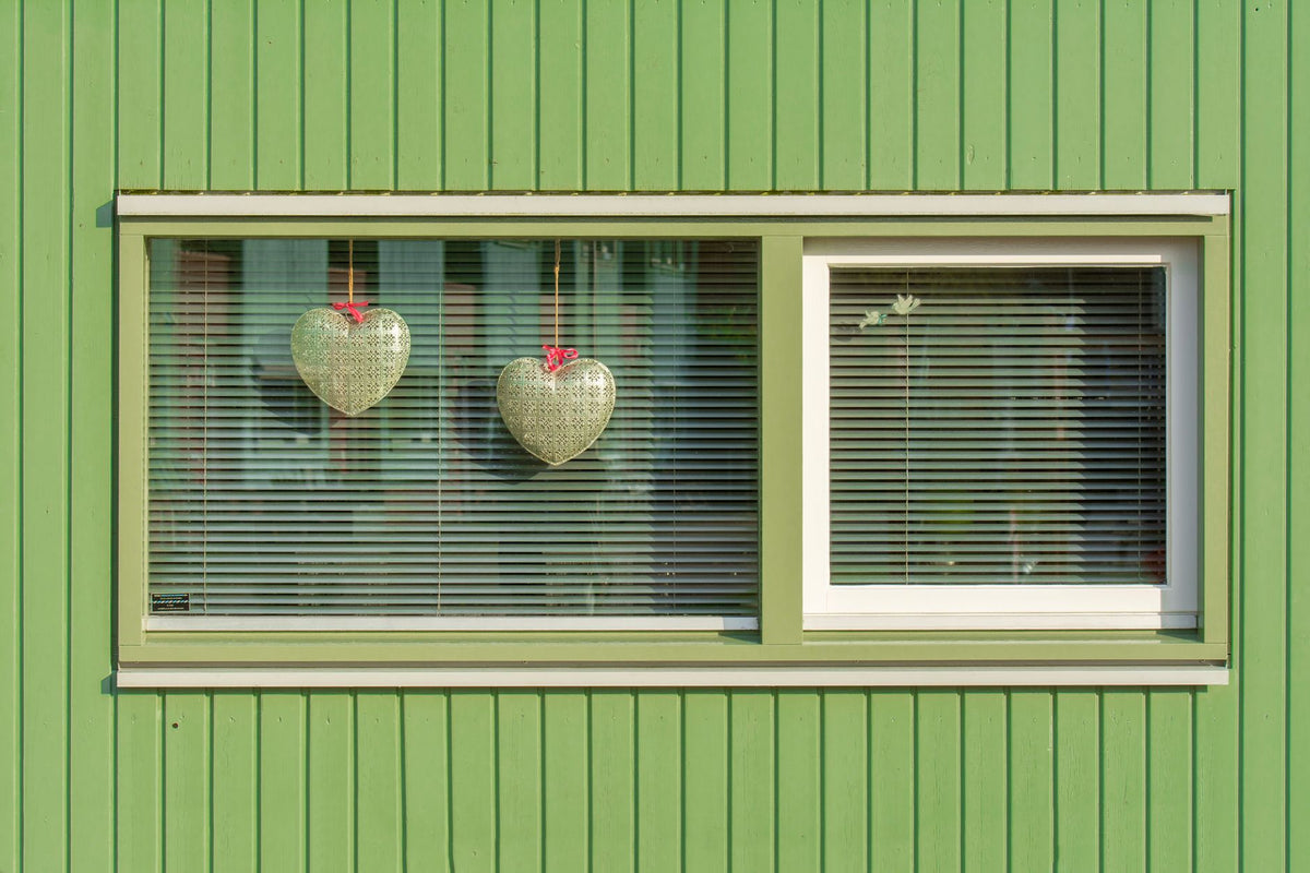 Green house exterior with two heart decorations in a window.