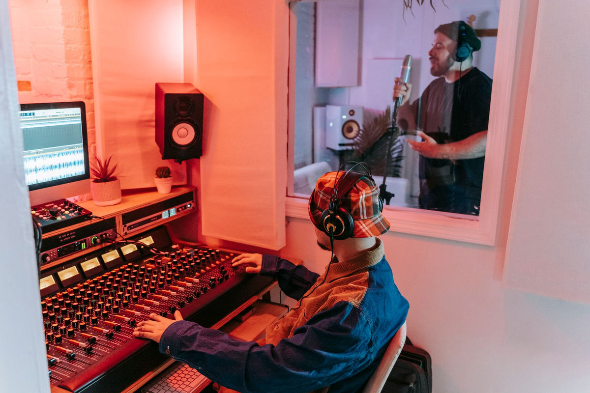 Two men engaged in a vocal recording session in a modern music studio, highlighting sound equipment.