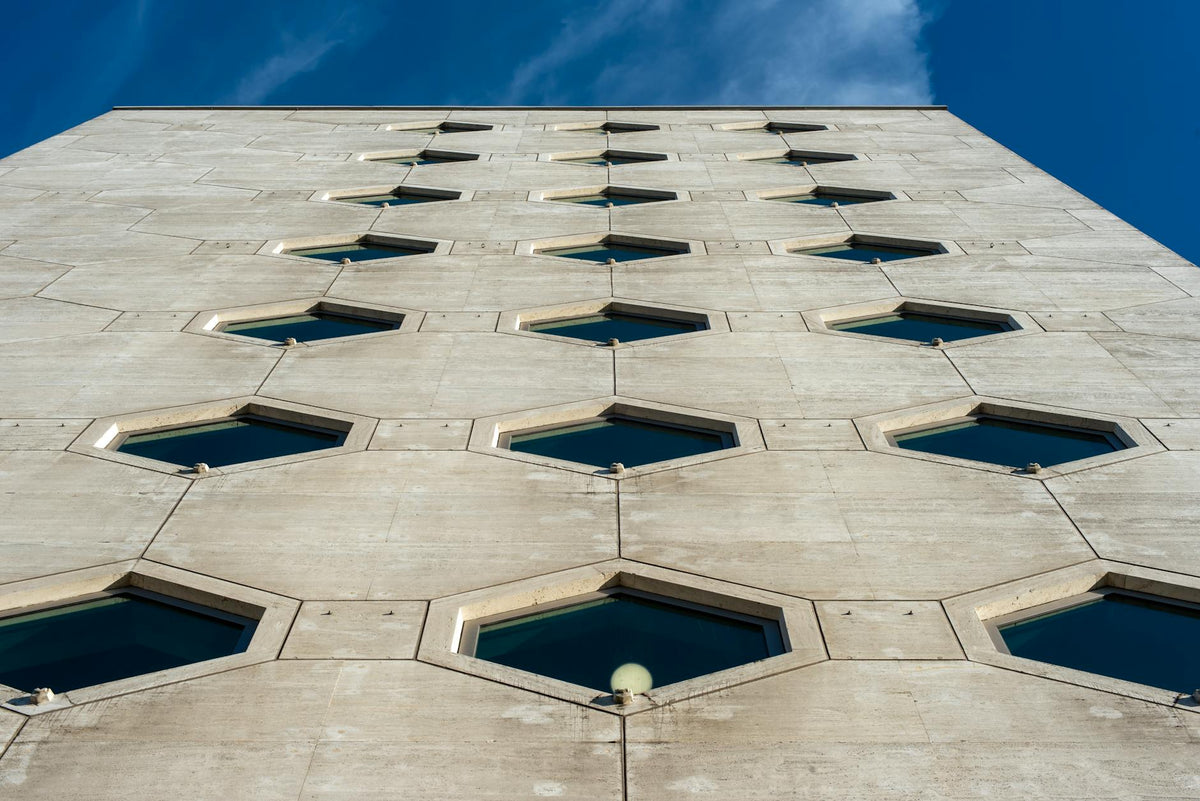 A modern building facade featuring hexagonal windows against a blue sky.