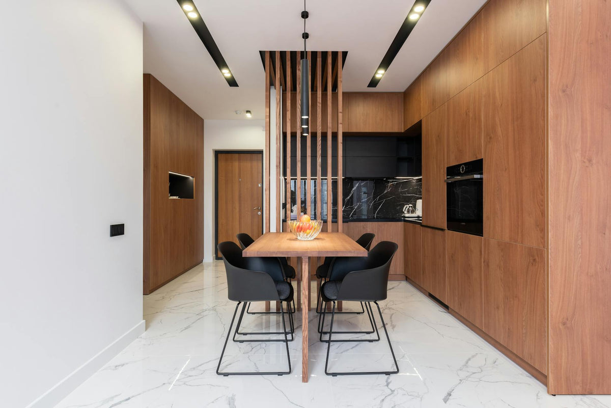 Table with chairs in spacious stylish kitchen with wooden furniture and modern appliances in luxury villa