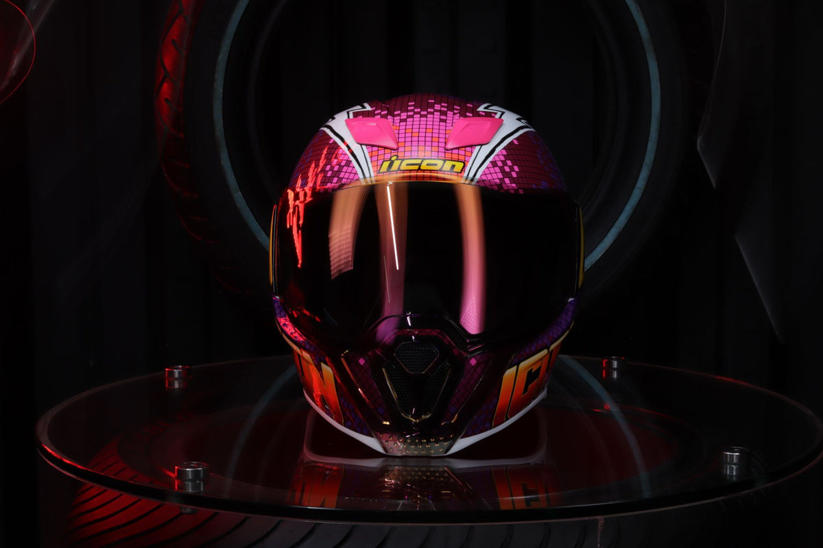 Vibrant motorcycle helmet with futuristic design displayed on a reflective surface.