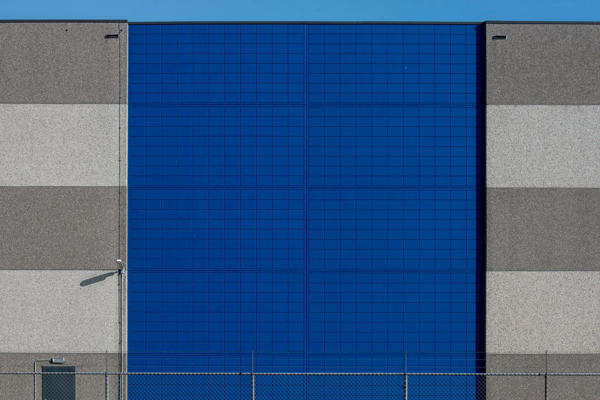 Photo of a modern industrial building showcasing a vibrant blue facade contrasted with neutral tones.