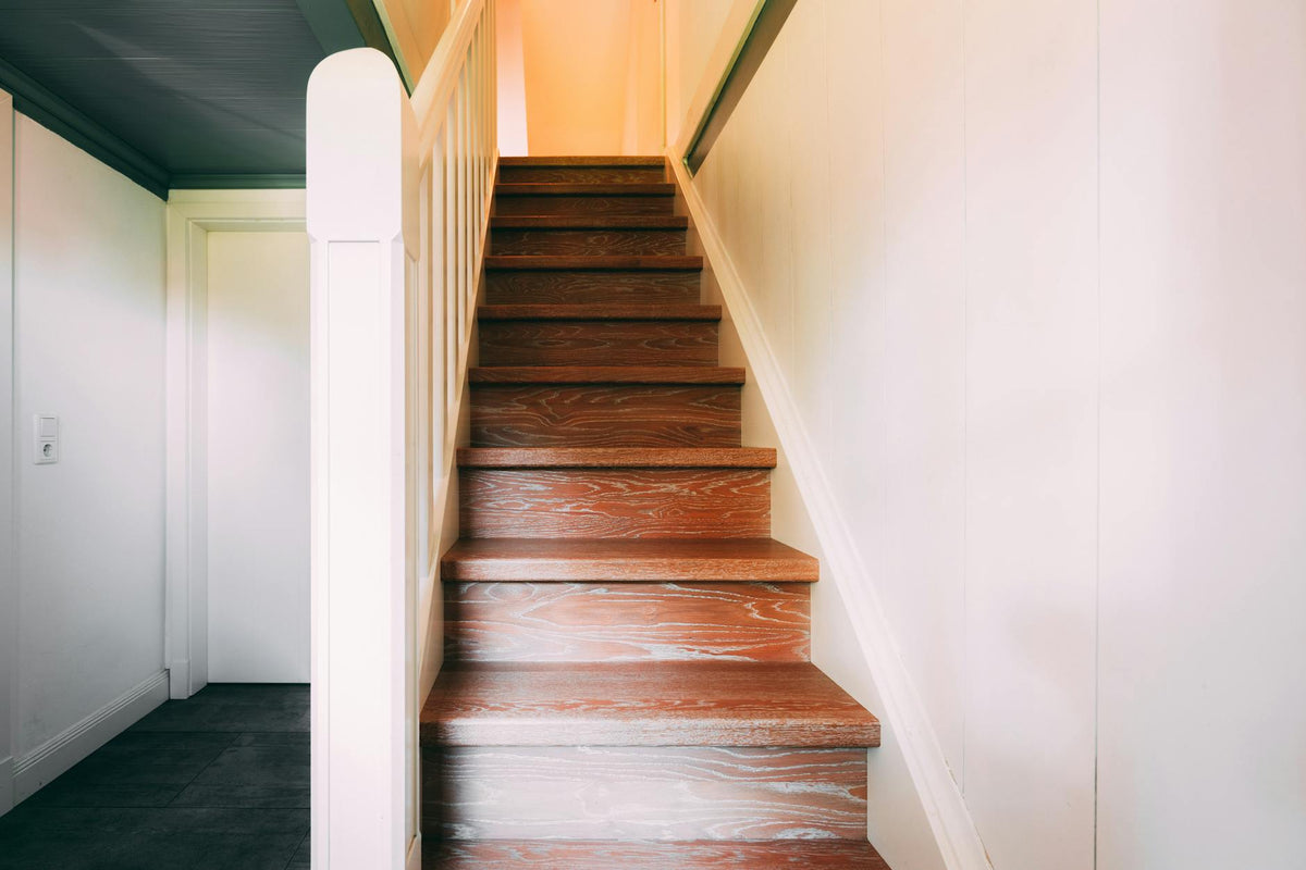 A classic wooden staircase leading to the upper floor in a brightly lit modern home.