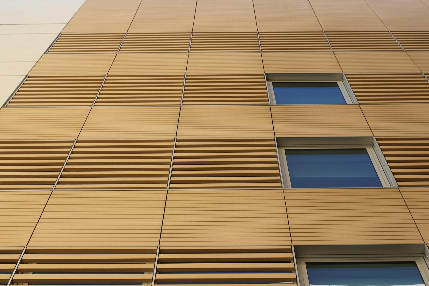 Sleek building facade with wooden slats and windows, showcasing modern architectural style.