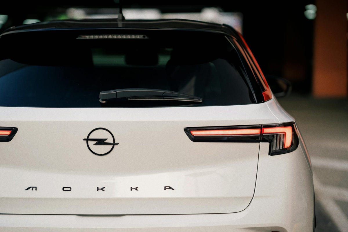 Close-up rear view of a white Opel Mokka in a garage setting, highlighting modern design.